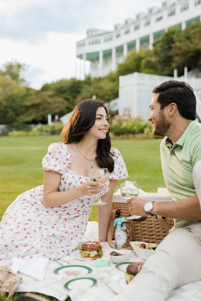 A young couple having a nice picnic with wine on the lawn of an upscale hotel - The Grand Hotel Hospitality Marketing