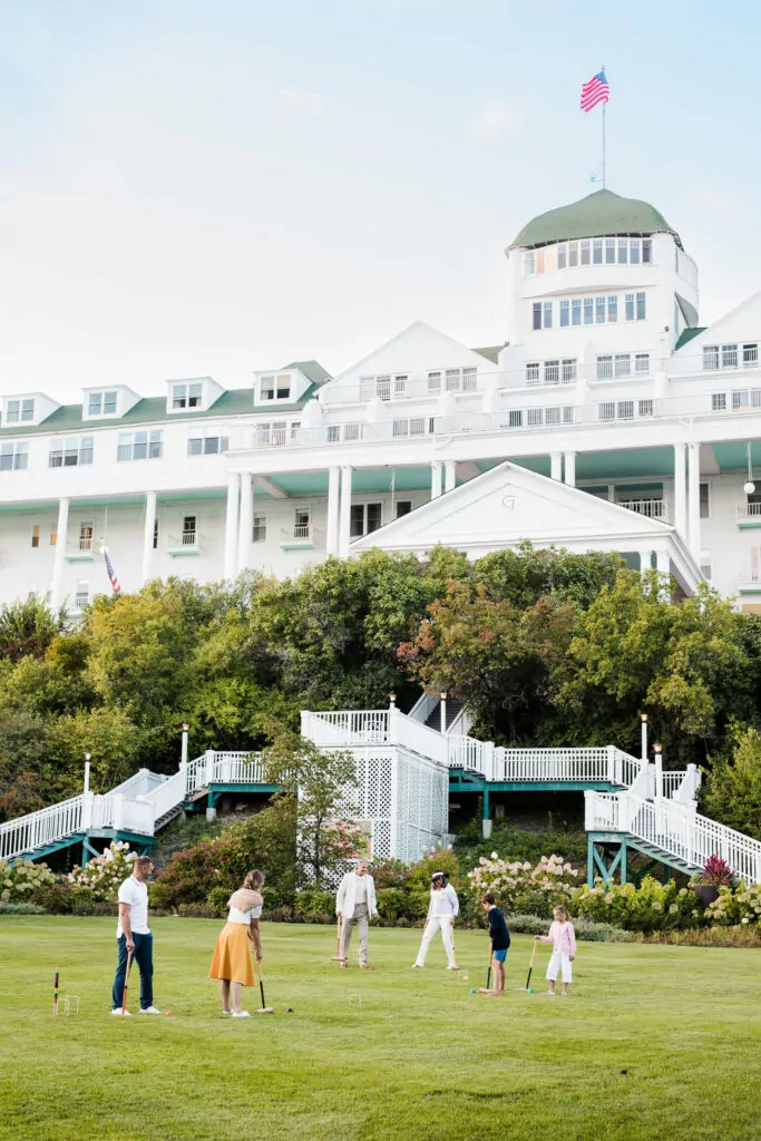 A family of six playing croquet on the lawn of a upscale hotel - The Grand Hotel Hospitality Marketing