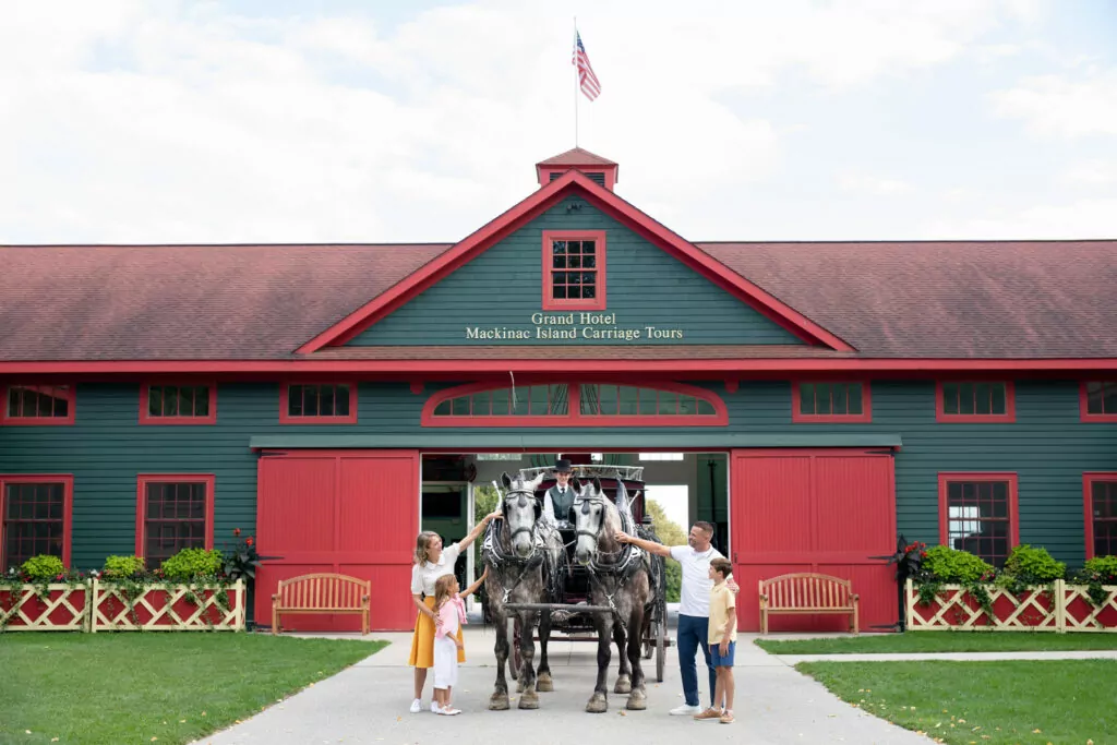 A family of four petting horses out side of the Makinac Island Carriage Tours - The Grand Hotel Hospitality Marketing