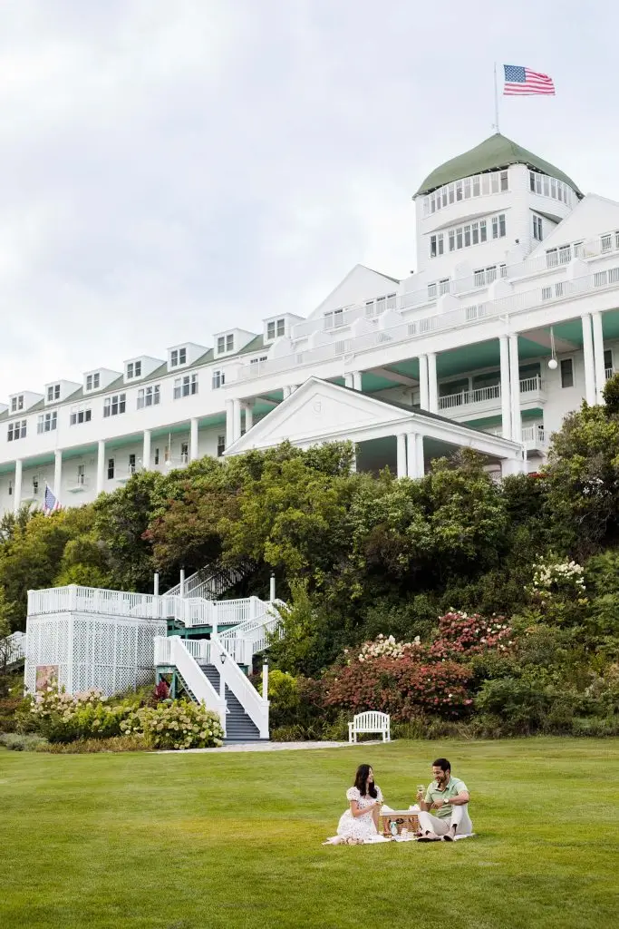 A young couple having a nice picnic with wine on the lawn of an upscale hotel - The Grand Hotel Hospitality Marketing